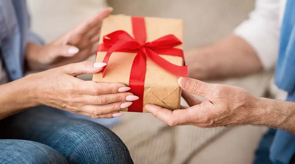 Eine Person überreicht einer anderen ein verpacktes Geschenk.